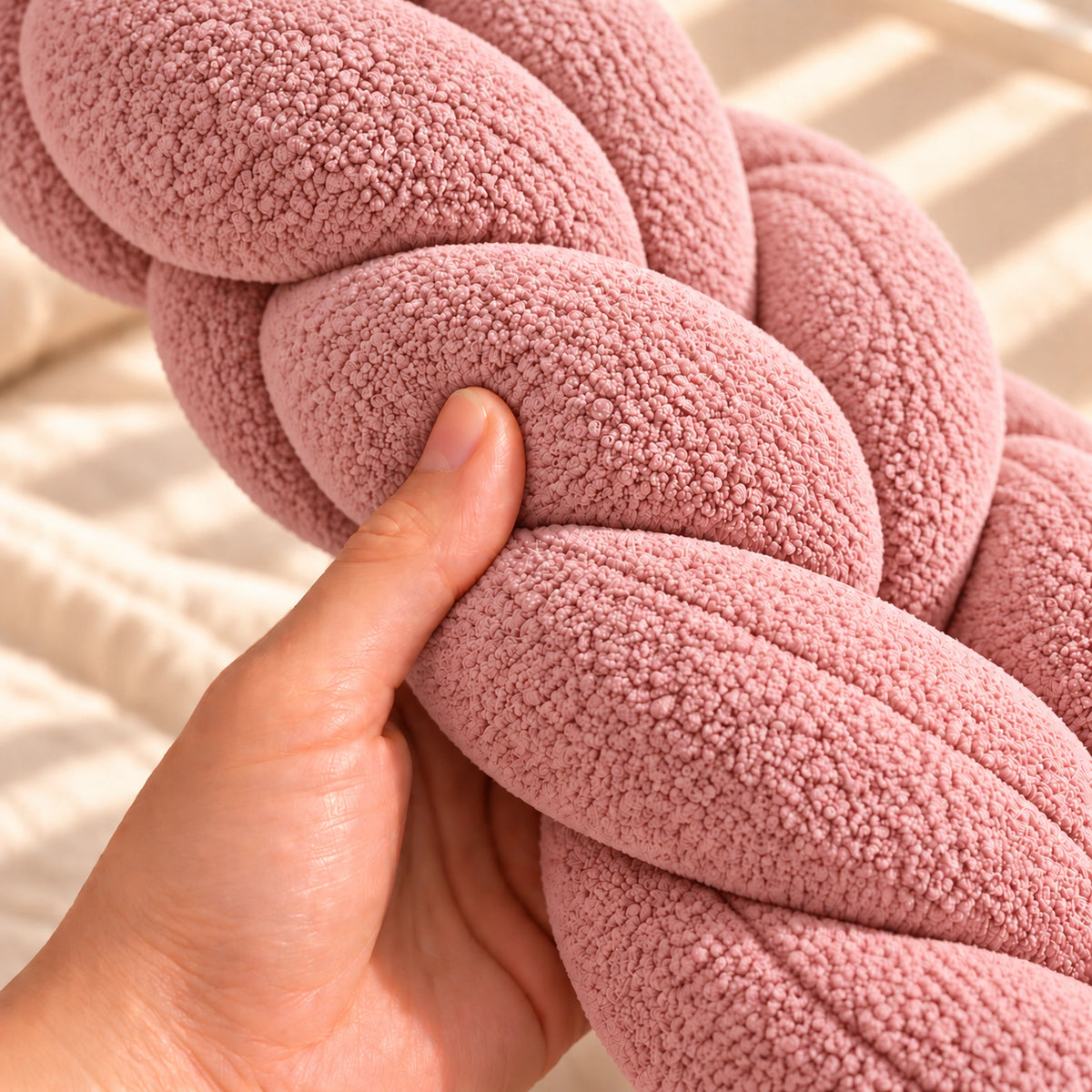 Tour de lit bébé tressé Rose, main pressant la tresse pour montrer le moelleux