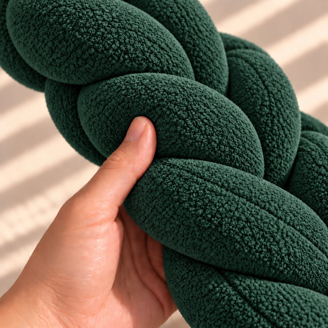 Tour de lit bébé tressé, coloris Vert sapin, main pressant la tresse pour montrer le moelleux